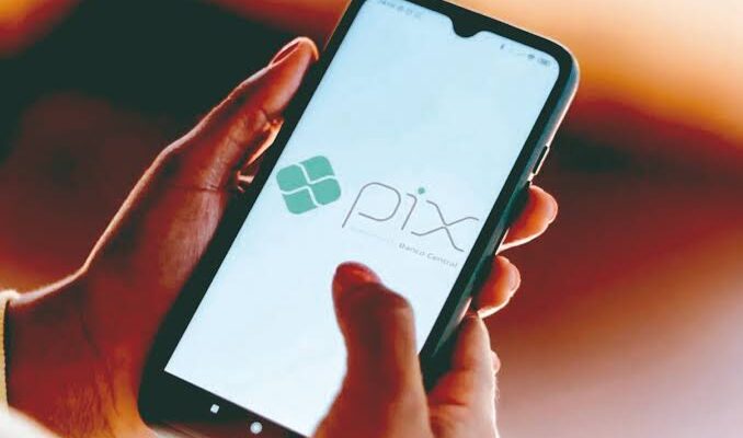 celular com usuário segurando e uma logomarca do pix na tela sendo mostrada
